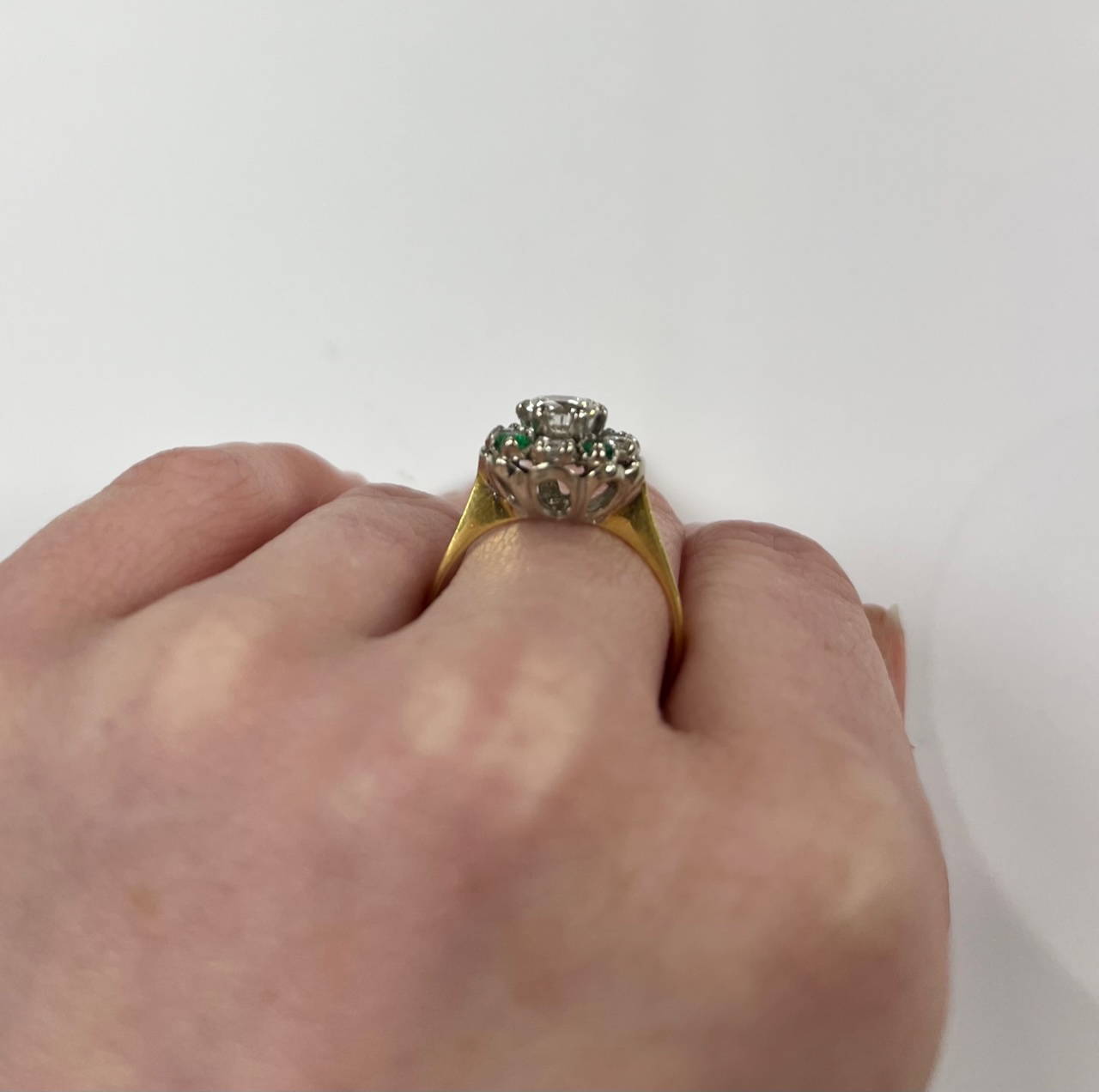 A yellow metal, diamond and emerald set flower head cluster ring, size P, gross weight 4 grams, the central diamond measuring approximately 5.5mm in diameter.